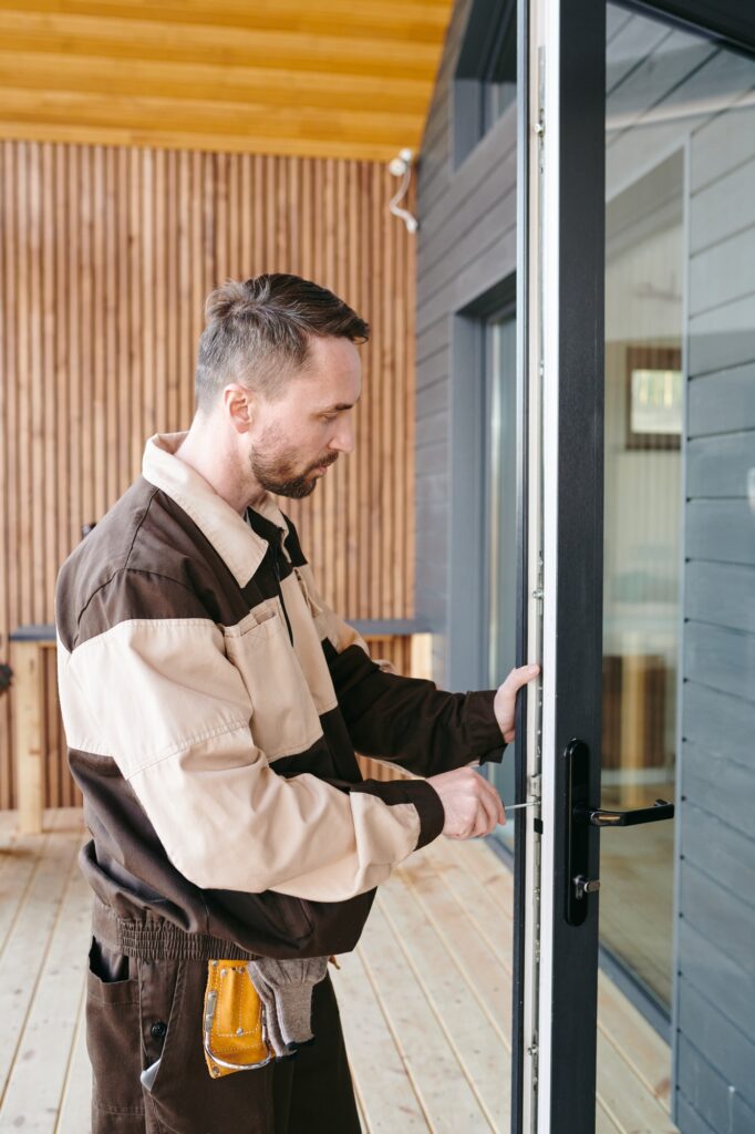A locksmith from Knoxmith Lock & Key in Knoxville, TN, performing a lock repair on a modern glass-paneled door.