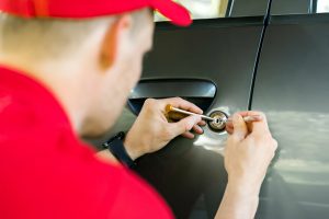 A Knoxmith Lock & Key technician in a red uniform unlocking a car door for a customer in Knoxville, TN.