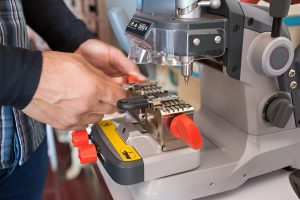 A professional locksmith from Knoxmith Lock & Key in Knoxville, TN, operating a modern key duplication machine to create a new key.