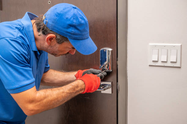 A professional locksmith from Knoxmith Lock & Key, wearing a blue uniform and gloves, carefully services a modern chrome key card lock on a commercial door in Knoxville.
